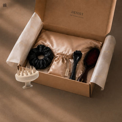 Vue de la box Densly complete : 5 accessoires pour stimuler la repousse capillaire et pour protéger les longueurs de la casse. Brosse massante cuir chevelu, dermaroller cheveux, brosse en nylon et poils de sanglier, chouchou en satin noir, taie d'oreiller en satin.